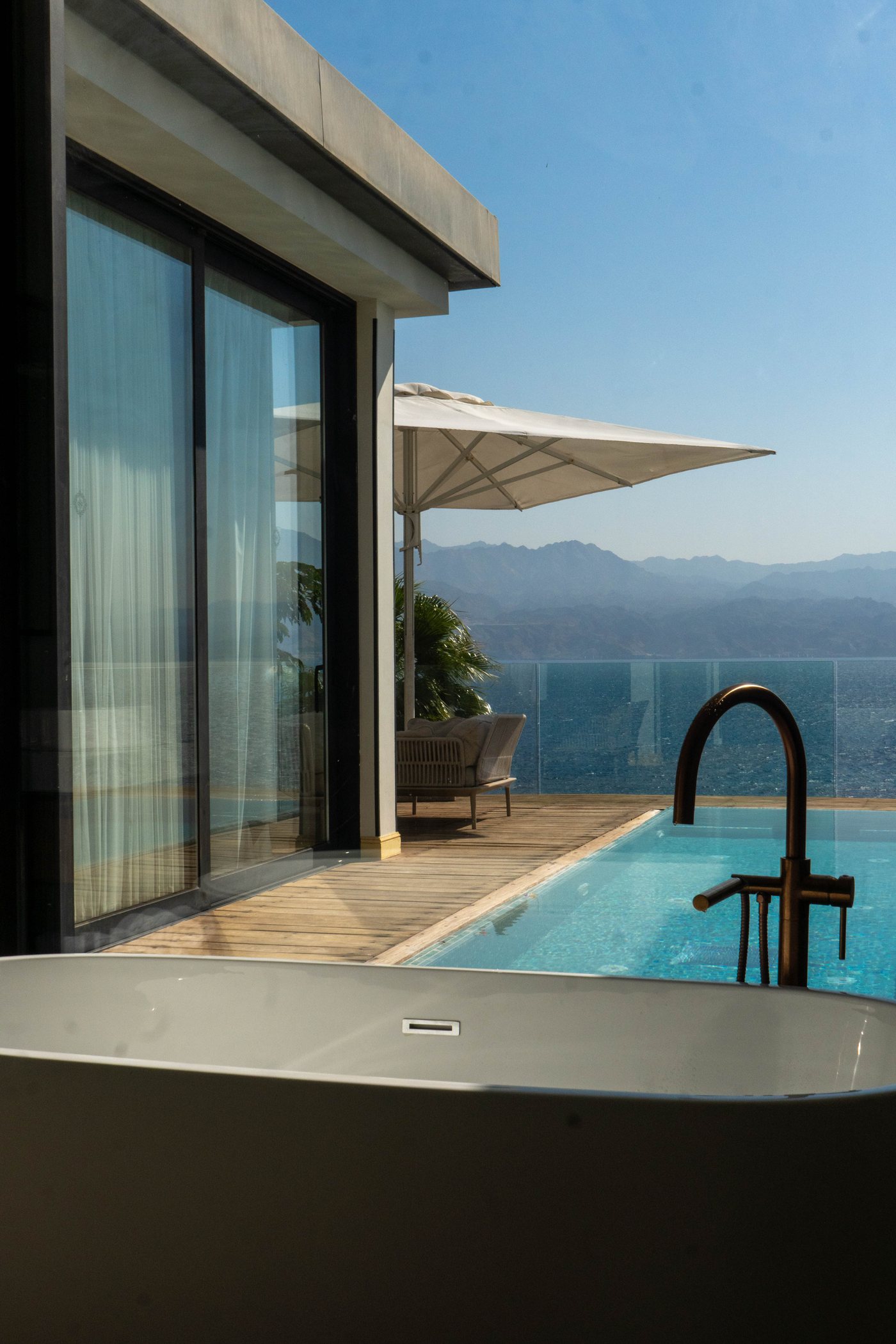 A bath beside a private pool, above the sea