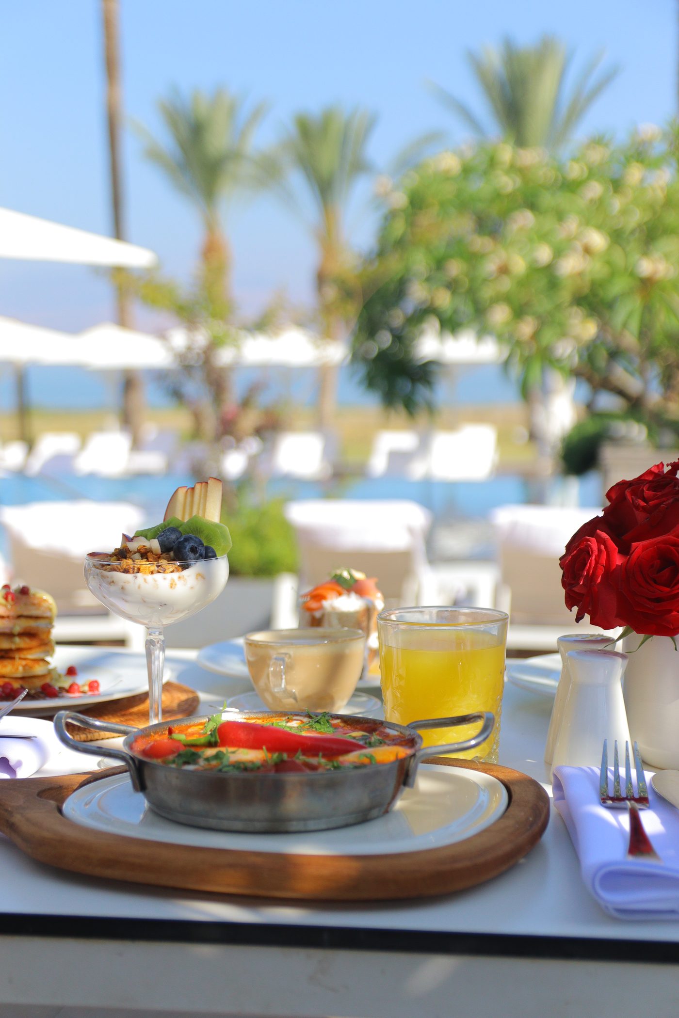 Breakfast laid out by the pool, roses on the table