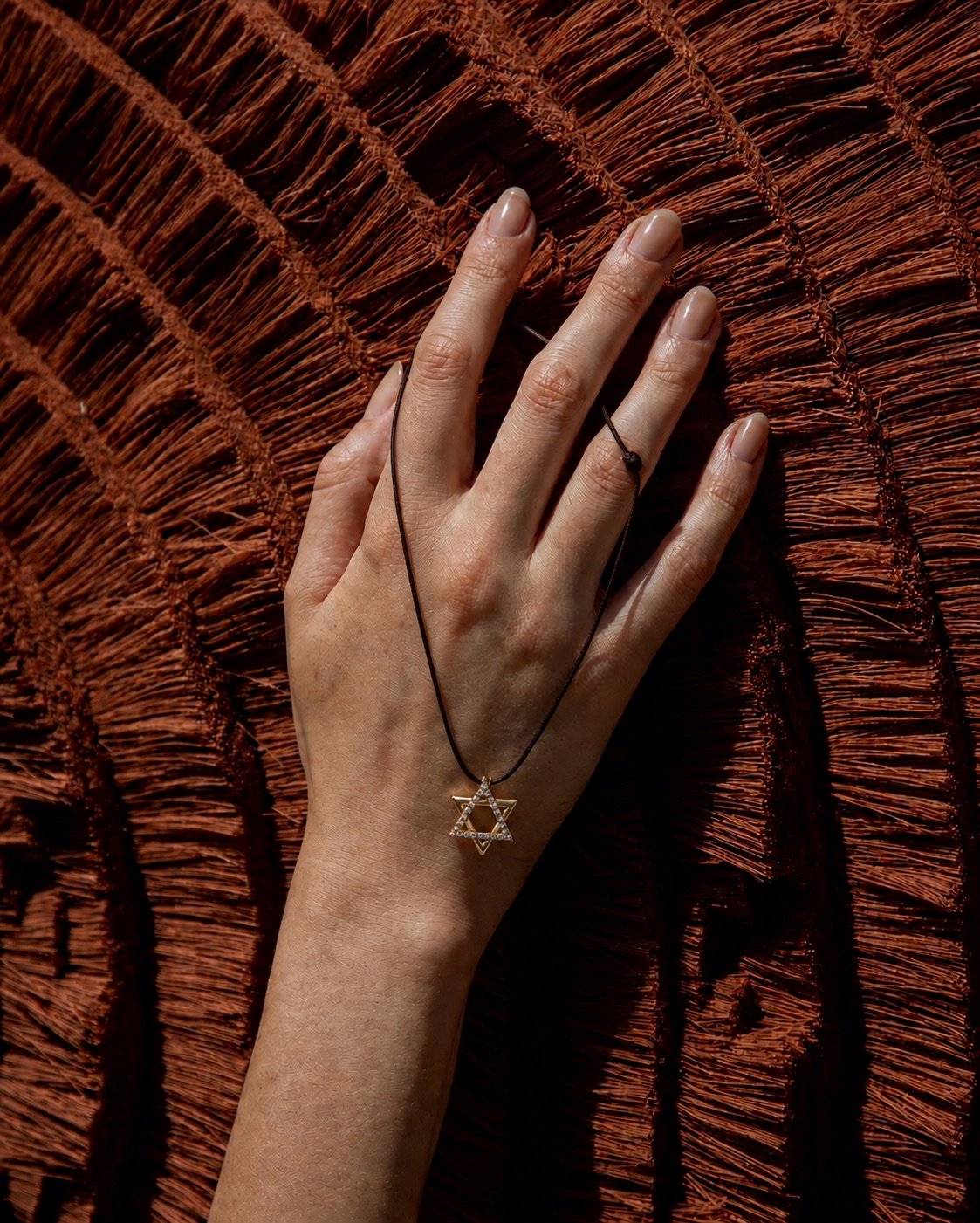 A hand on raffia, the chain falling across it