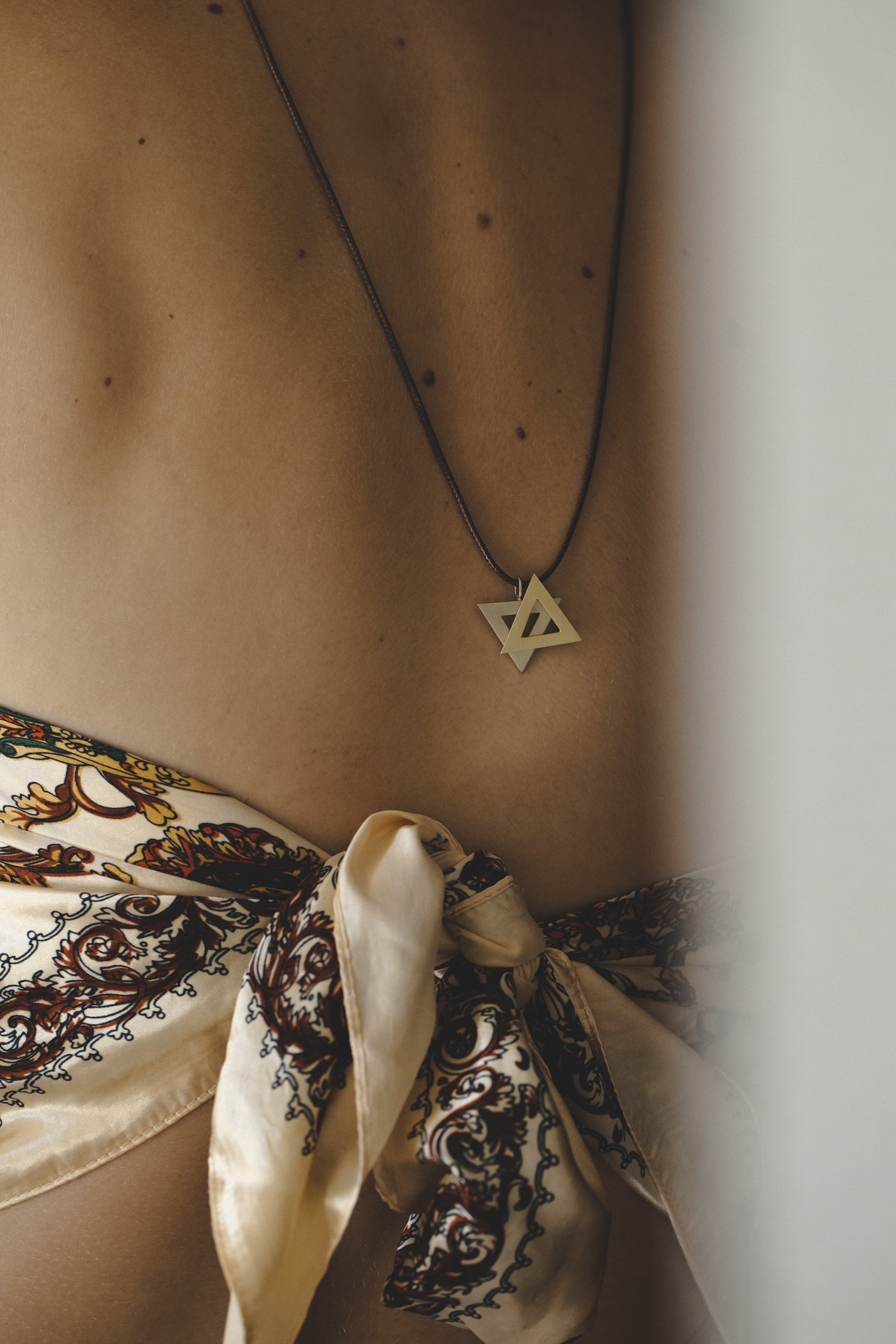 The star at the nape, above the knotted scarf